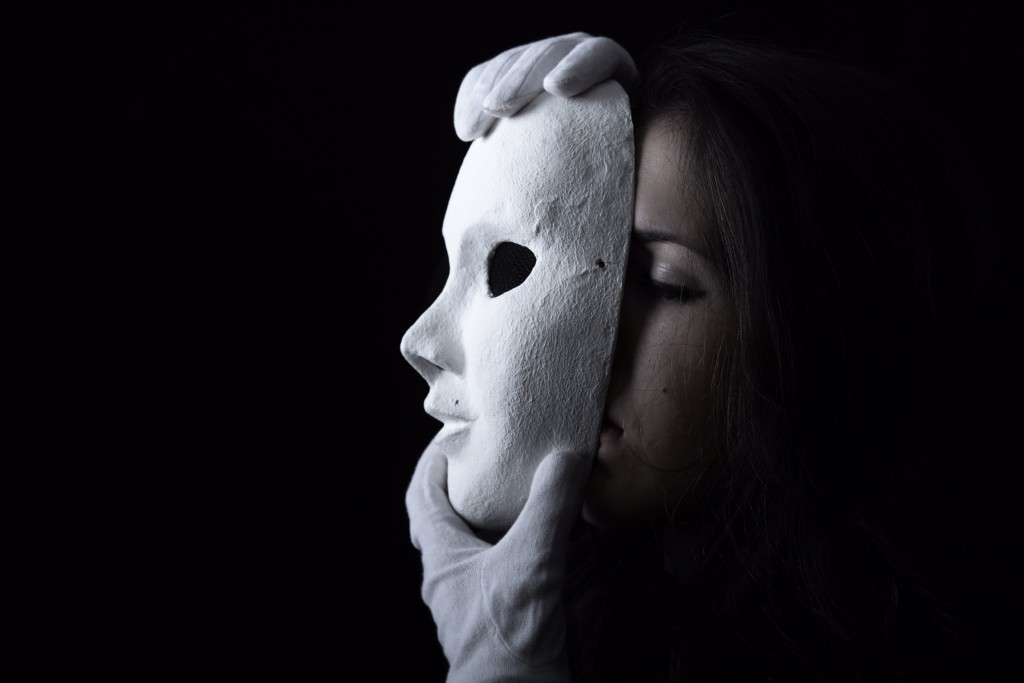 brunette girl holding a white theatrical mask